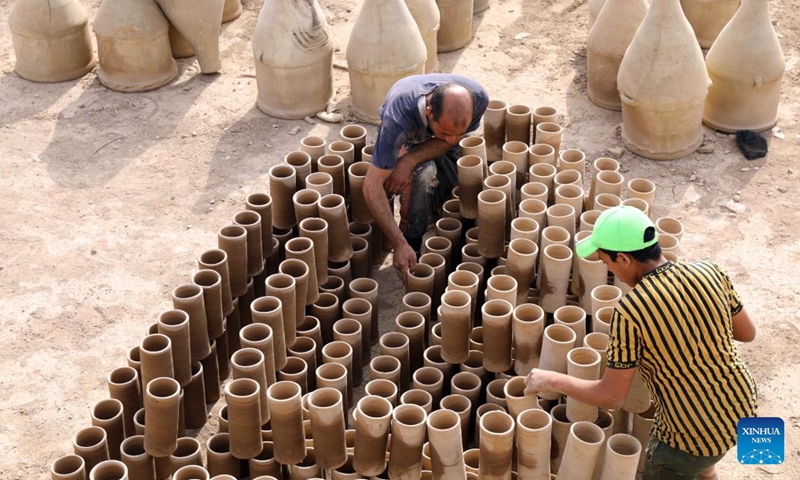 Safaa al-Kawaz (L), a pottery workshop owner, arranges earthenware together with an assistant in the Nahrawan area near Baghdad, Iraq, May 27, 2023. Pottery-making in Iraq has been an enduring profession which is deeply rooted in the civilizations of Mesopotamia. (Xinhua/Khalil Dawood)