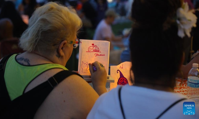 Two women draw on lanterns during the Water Lantern Festival held in Houston, Texas, the United States, May 27, 2023. (Xinhua/Xu Jianmei)