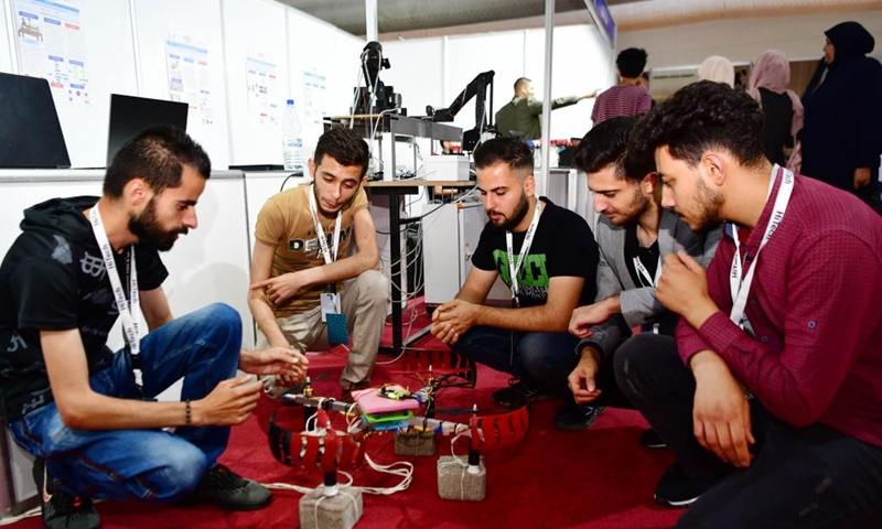 Young men are seen at an exhibition of technologies in Damascus, Syria, on June 10, 2023. (Photo by Ammar Safarjalani/Xinhua)