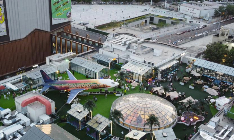 This aerial photo taken on June 2, 2023 shows people having fun on top of a commercial complex in Heping District, north China's Tianjin. Transformed from four vacant buildings, a commercial complex was unveiled in Heping District of Tianjin recently. This commercial complex not only offers people with shopping malls but also leisure spaces such as rooftop parks and pocket parks. The airplane themed bar and other entertainment spaces located on top of the commercial complex gained popularity for the surrounding business area. (Xinhua/Zhao Zishuo)