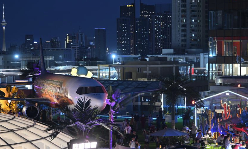 This photo taken on June 2, 2023 shows people having fun on top of a commercial complex in Heping District, north China's Tianjin. Transformed from four vacant buildings, a commercial complex was unveiled in Heping District of Tianjin recently. This commercial complex not only offers people with shopping malls but also leisure spaces such as rooftop parks and pocket parks. The airplane themed bar and other entertainment spaces located on top of the commercial complex gained popularity for the surrounding business area. (Xinhua/Li Ran)