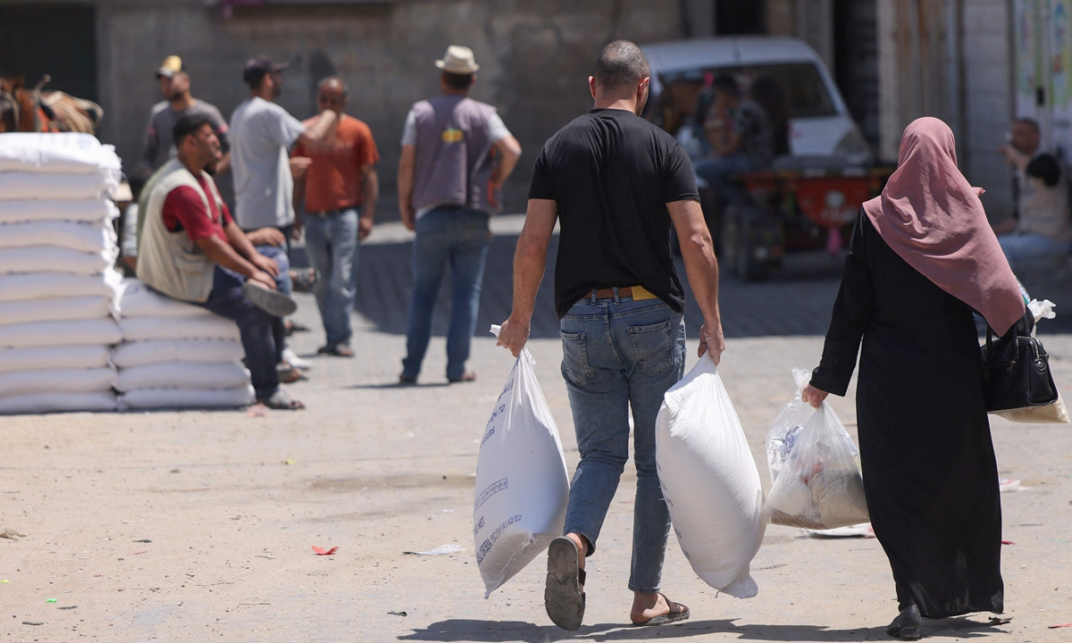 Palestinians carry their share of food aid provided to poor families at the United Nations Relief and Works Agency for Palestine Refugees (UNRWA) distribution center, in the Al-Shati refugee camp in Gaza city on June 5, 2023. At present, some 5.9 million Palestine refugees are eligible for UNRWA services, according to the agency. Photo: VCG