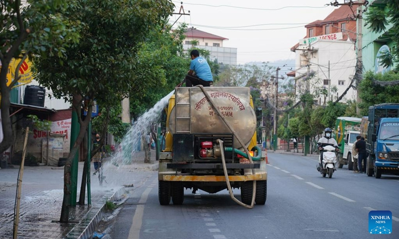 A worker sprinkles water on trees on a street on World Environment Day in Lalitpur, Nepal, June 5, 2023.(Photo: Xinhua)