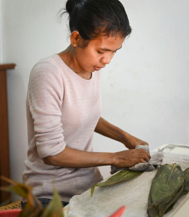 A staff member prepares leaves for the wrapping process at a shop for rice dumplings at Malacca, Malaysia, June 17, 2023. The Nyonya Chang, also known as the Butterfly Pea Rice Dumplings, is a fusion delicacy of traditional Chinese rice dumplings and the local Peranakan culture, also known as Baba-Nyonya culture. (Xinhua/Cheng Yiheng)