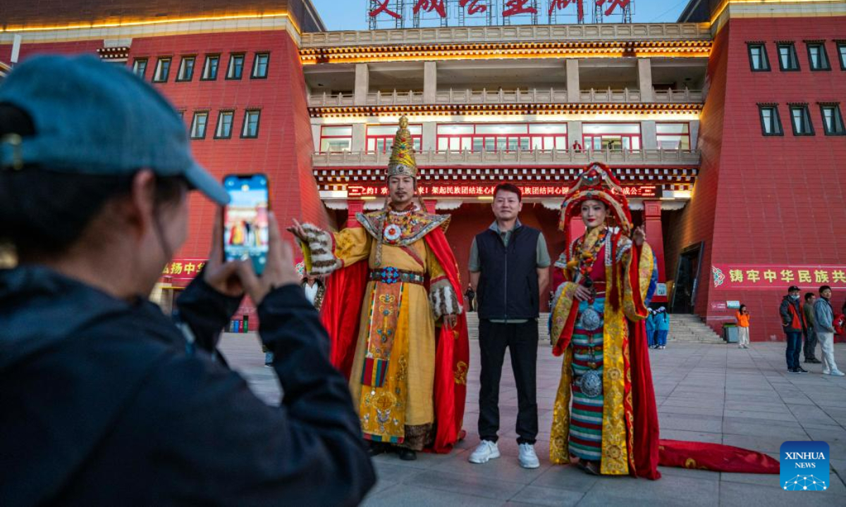 A tourist poses for photos with actors in front of a theater in Lhasa, southwest China's Tibet Autonomous Region, June 6, 2023. Photo:Xinhua