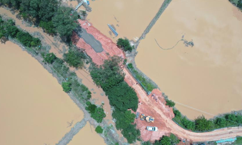 This aerial photo taken on June 11, 2023 shows workers repairing dyke breaches caused by floods after heavy rainfall in Baisha Town of Hepu County, south China's Guangxi Zhuang Autonomous Region. (Xinhua/Lu Boan)