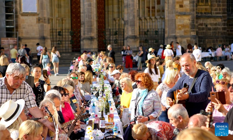 People take part in a long table event at Prague Castle in Prague, the Czech Republic, on June 12, 2023. A roughly 400-meter-long table in the shape of a heart was set up around St. Vitus Cathedral at Prague Castle on Monday. Prague's residents and visitors were welcomed to join the event with their own dishes and share with others(Photo: Xinhua)