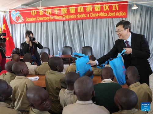 Chinese Ambassador to Zimbabwe Zhou Ding hands out stationery bags to children during a donation ceremony in Harare June 13, 2023. The Chinese Embassy in Zimbabwe held a donation ceremony on Tuesday in Harare, capital of Zimbabwe, to bring cheer to orphans and other vulnerable children in the country.(Photo: Xinhua)