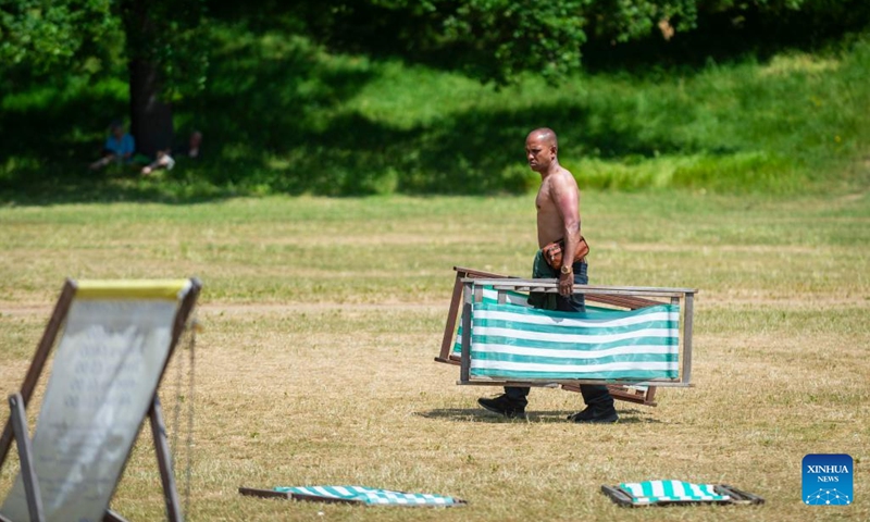 A man carries deckchairs at Hyde Park in London, Britain, on June 15, 2023. Parts of Britain are in the grip of a heatwave currently.(Photo: Xinhua)