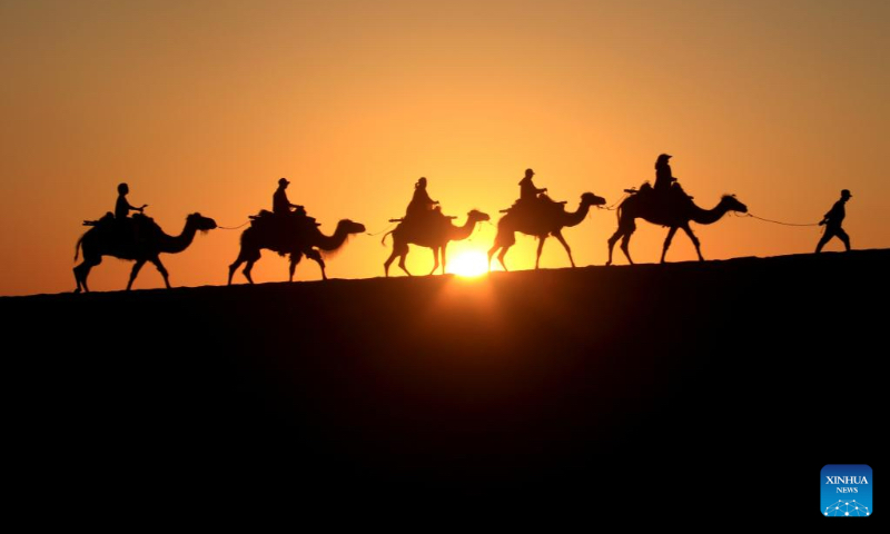 Visitors ride camels at the mingsha mountain and crescent spring scenic spot in dunhuang, northwest China's Gansu Province, June 7, 2023. As a key pass along the ancient Silk Road, Dunhuang is home to the Mogao Grottoes, a UNESCO World Heritage Site that boasts a vast collection of Buddhist artworks -- more than 2,000 colored sculptures and 45,000 square meters of murals are located in 735 caves. (Photo by Zhang Xiaoliang/Xinhua)