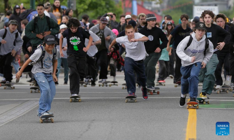 People ride down the street with their skateboards to celebrate the annual 