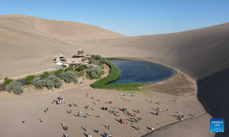 This aerial photo taken on June 7, 2023 shows the mingsha mountain and crescent spring scenic spot in dunhuang, northwest China's Gansu Province. As a key pass along the ancient Silk Road, Dunhuang is home to the Mogao Grottoes, a UNESCO World Heritage Site that boasts a vast collection of Buddhist artworks -- more than 2,000 colored sculptures and 45,000 square meters of murals are located in 735 caves. (Xinhua/Zhang Zhimin)