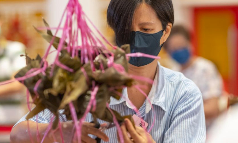 A participant makes Zongzi, a pyramid-shaped glutinous rice dumpling wrapped in bamboo or reed leaves, during a contest in celebration of the upcoming Chinese Dragon Boat Festival in Kuala Lumpur, Malaysia, June 18, 2023. (Photo by Chong Voon Chung/Xinhua)