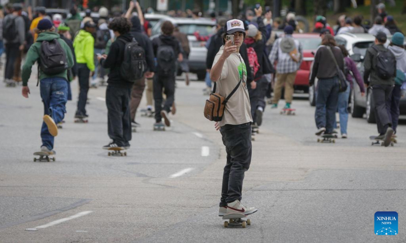 People ride down the street with their skateboards to celebrate the annual 