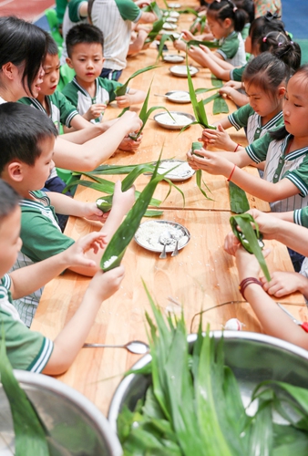 Teachers help children experience making zongzi in Huaying, Southwest China's Sichuan Province, on June 19, 2023. Photo: IC