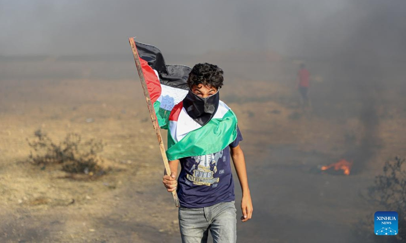 A Palestinian protester holds a flag during a protest against the killing of five Palestinians near the fence of the Gaza-Israel border, east of Gaza City, on June 19, 2023.(Photo: Xinhua)