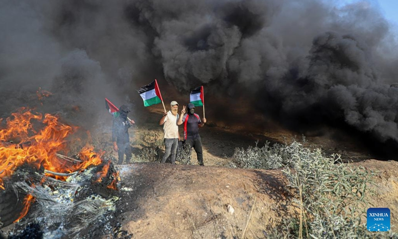 Palestinian protesters hold flags during a protest against the killing of five Palestinians near the fence of the Gaza-Israel border, east of Gaza City, on June 19, 2023.(Photo: Xinhua)