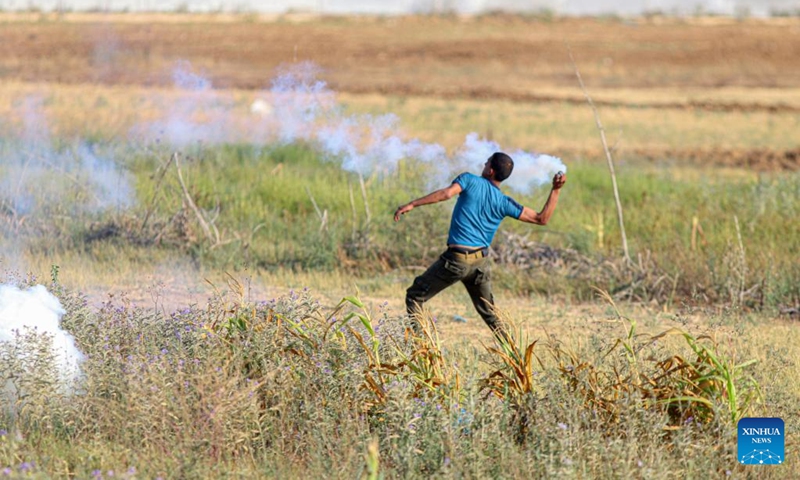 A Palestinian protester throws a tear gas canister fired by an Israeli soldier during a protest against the killing of five Palestinians near the fence of the Gaza-Israel border, east of Gaza City, on June 19, 2023.(Photo: Xinhua)