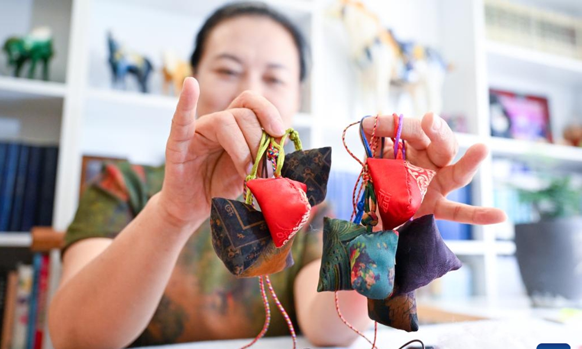 Chen Yuqiu shows sachets she made at home in Jilin, northeast China's Jilin Province, June 20, 2023. Chen Yuqiu, 55 years old, is an inheritor of the national-level intangible cultural heritage of Manchu cheongsam making. In order to make people aware of the traditional Chinese culture and Manchu cheongsam, she taught people to make sachets at the Jilin Museum and sent them to citizens before the Dragon Boat Festival. (Xinhua/Yan Linyun)