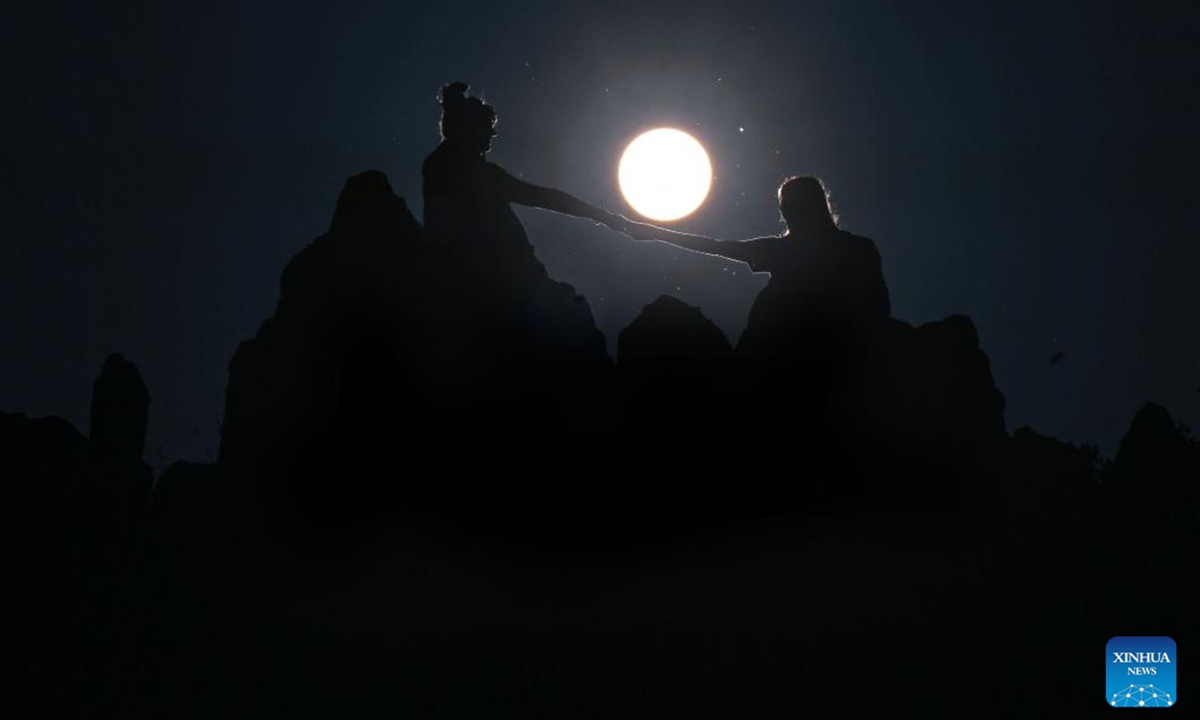 People pose for a photo as the sun rises on the summer solstice at the ancient megalithic observatory of Kokino, North Macedonia, June 21, 2023. (Photo by Tomislav Georgiev/Xinhua)

