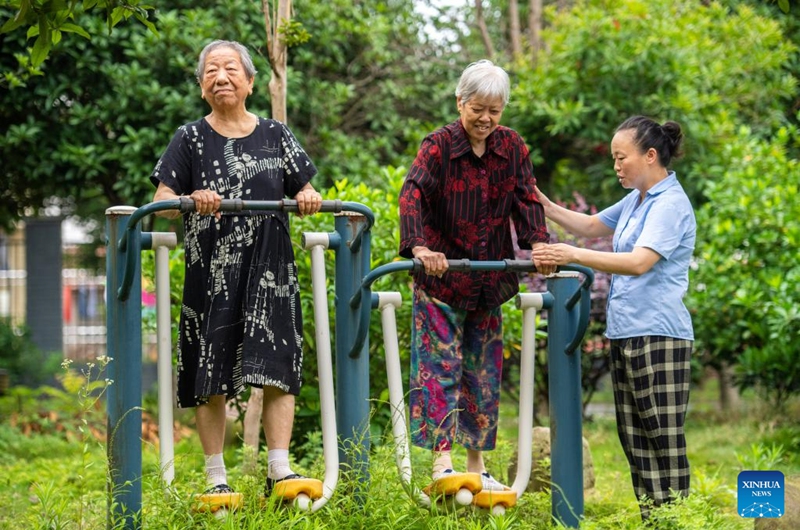 Senior residents exercise with the help of a staff member at a social welfare center in Hanshou County of Changde City, central China's Hunan Province, June 20, 2023. The city of Changde has scaled up efforts to develop an elderly care service system composed mainly of in-home cares, community services, institutional and medical cares. (Xinhua/Chen Sihan)