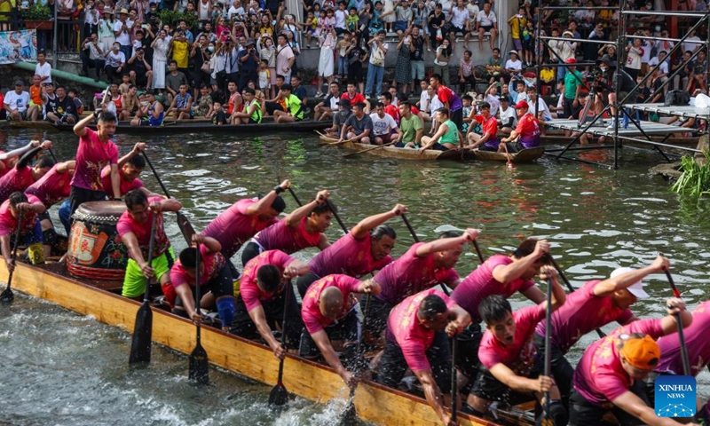 People watch the dragon boat race in Diejiao Township of Foshan, south China's Guangdong Province, June 22, 2023. With a narrow and winding river, Diejiao Township holds the dragon boat race annually for the Dragon Boat Festival. Participants must drift the 25-meter-long vessel around shapes curved like S, C and L at full speed. (Xinhua/Liu Dawei)