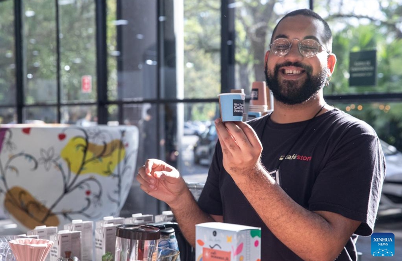 A staff member presents a cup of coffee during the Sao Paulo Coffee Festival in Sao Paulo, Brazil, on June 23, 2023. (Xinhua/Wang Tiancong)