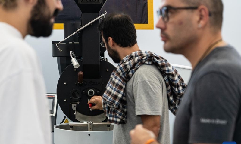 A visitor watches coffee roasting equipment during the Sao Paulo Coffee Festival in Sao Paulo, Brazil, on June 23, 2023. (Xinhua/Wang Tiancong)