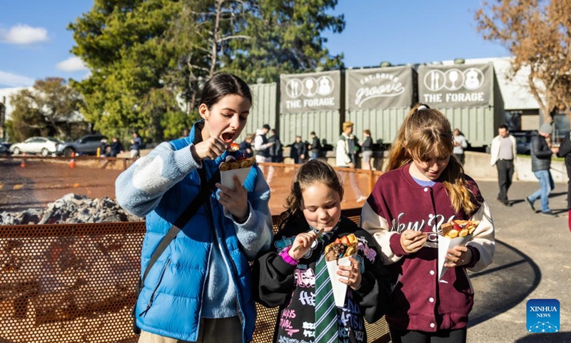 People attend a winter food festival in Canberra, Australia, on June 24, 2023. A winter food festival was held on Saturday to provide street food and other products by local cafes, food trucks, wineries and breweries for customers. (Photo by Chu Chen/Xinhua)