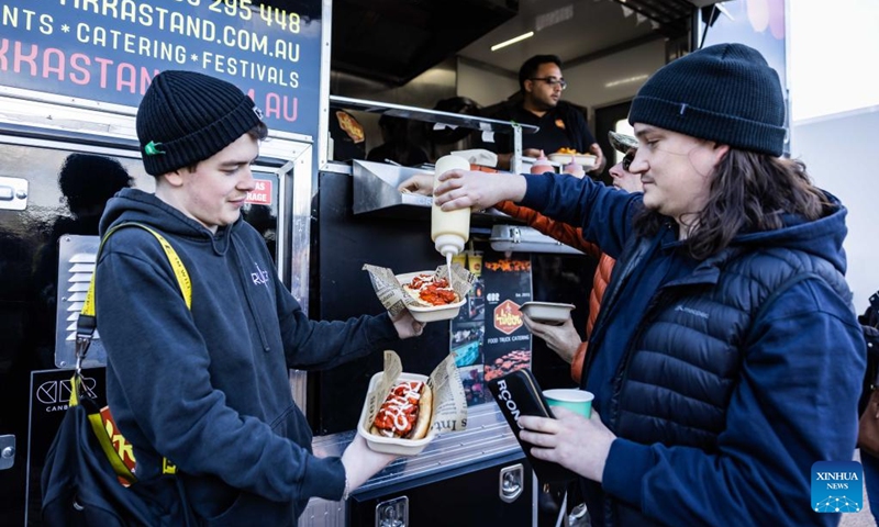 People season their snacks at a winter food festival in Canberra, Australia, on June 24, 2023. A winter food festival was held on Saturday to provide street food and other products by local cafes, food trucks, wineries and breweries for customers. (Photo by Chu Chen/Xinhua)