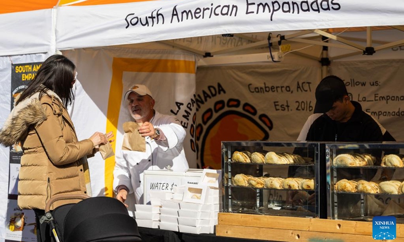 A visitor patronizes a stall at a winter food festival in Canberra, Australia, on June 24, 2023. A winter food festival was held on Saturday to provide street food and other products by local cafes, food trucks, wineries and breweries for customers. (Photo by Chu Chen/Xinhua)