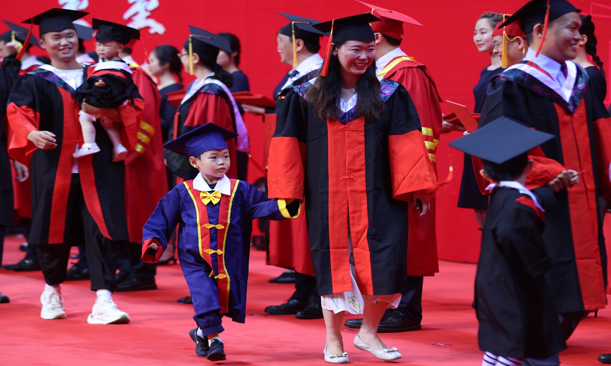 Many PhD graduates bring their children to the graduation ceremony at Nanjing Medical University on June 28, 2023, so that their children can witness the important moment together. Photo: IC