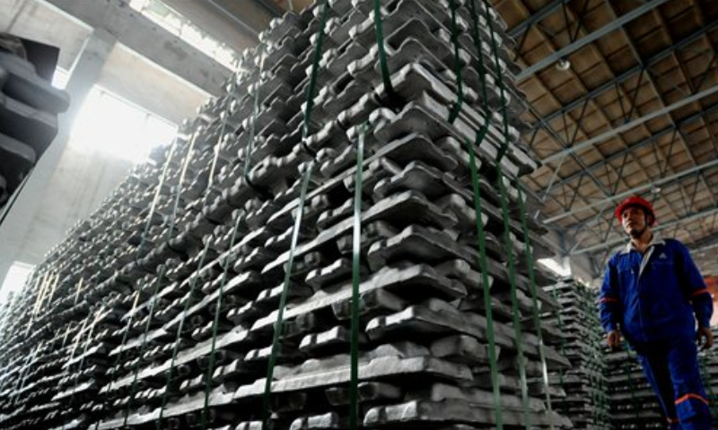 A worker passes by piles of aluminum ingots at a plant under Aluminum Corp of China. File Photo: VCG