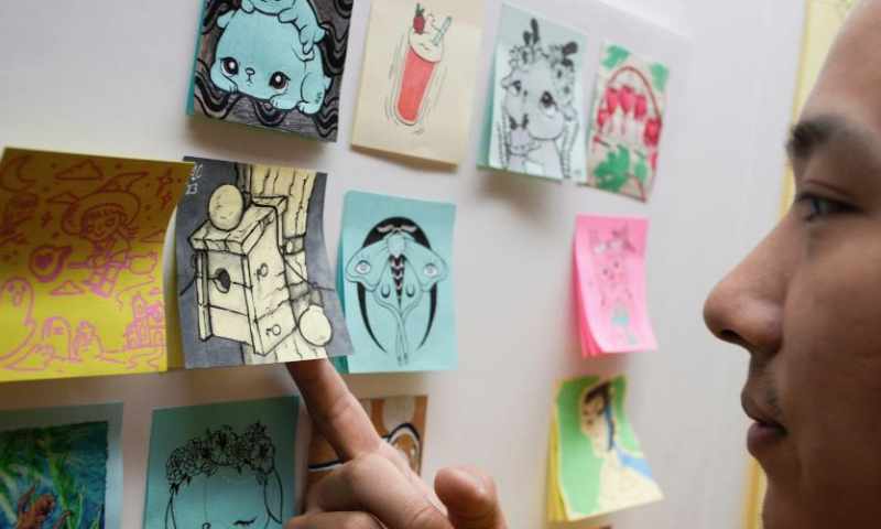 A man takes a close look at the artworks during the Post-it Note Art Show in Vancouver, British Columbia, Canada, on July 8, 2023. (Photo by Liang Sen/Xinhua)