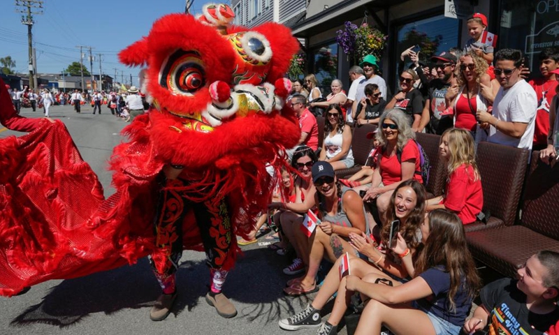 A lion dance performer interacts with people during the Salmon Festival Parade in Richmond, British Columbia, Canada, on July 1, 2023. (Photo by Liang Sen/Xinhua)