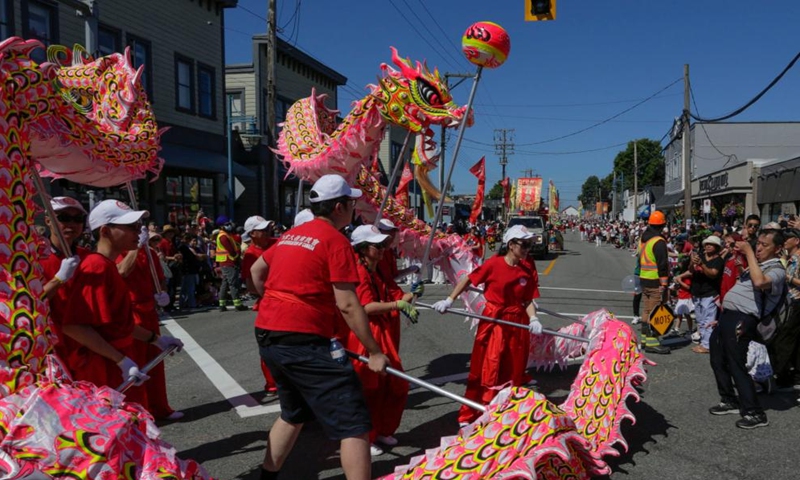 Spectators watch dragon dance during the Salmon Festival Parade in Richmond, British Columbia, Canada, on July 1, 2023. (Photo by Liang Sen/Xinhua)