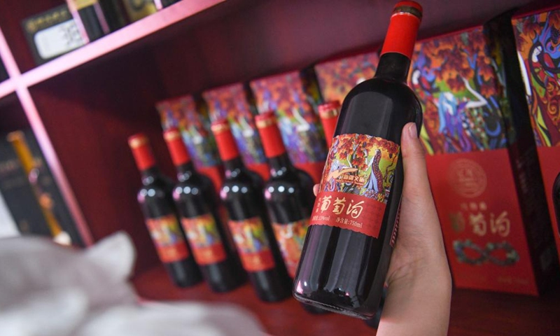 A tourist selects wine products at the Grape Valley scenic area in Turpan, northwest China's Xinjiang Uygur Autonomous Region, June 26, 2023. The city of Turpan has received 2.53 million tourist visits from June 1 to 28, an increase of nearly 40 percent over the same period in 2022. (Photo: Xinhua)