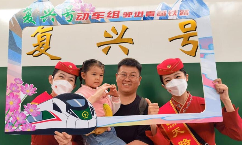 Attendants pose for a photo with passengers in front of a Fuxing bullet train on the Xining-Golmud section of the Qinghai-Tibet Railway in Xining, northwest China's Qinghai Province, July 1, 2023. (Photo: China News Service/Qi Zengpei)