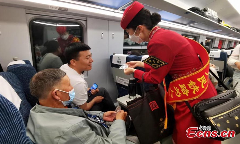 An attendant offers gifts to passengers on Fuxing bullet train C891 on the Xining-Golmud section of the Qinghai-Tibet Railway in northwest China's Qinghai Province, July 1, 2023. (Photo: China News Service/Qi Zengpei)