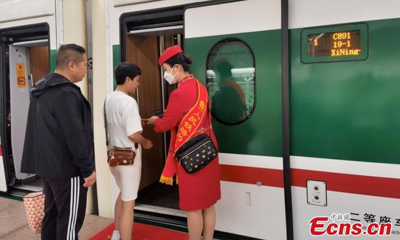 An attendant of Fuxing bullet train C891 on the Xining-Golmud section of the Qinghai-Tibet Railway checks passengers' tickets in Xining, northwest China's Qinghai Province, July 1, 2023. (Photo: China News Service/Qi Zengpei)