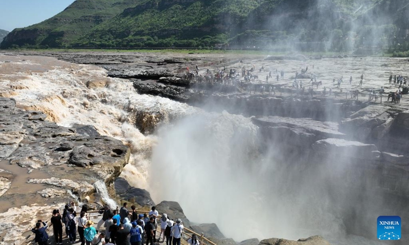 This aerial photo taken on July 3, 2023 shows tourists viewing the scenery of the Hukou Waterfall on the Yellow River, on the border area between north China's Shanxi and northwest China's Shaanxi provinces.(Photo: Xinhua)