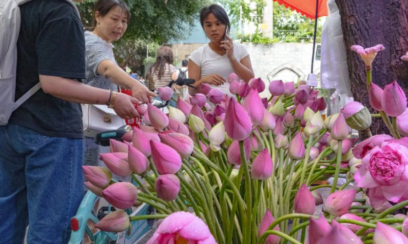 People choose lotus buds at a flower stall in Chengdu of southwest China's Sichuan Province, on July 14, 2023. The 31st FISU Summer World University Games is scheduled to take place in Chengdu from July 28 to August 8, 2023. (Xinhua/Tang Wenhao)