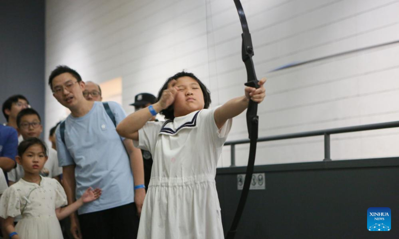 A girl experiences archery at a night fair at Minhang Museum of Shanghai in east China to experience the traditional Mongolian custom, July 21, 2023. (Xinhua/Xin Mengchen)