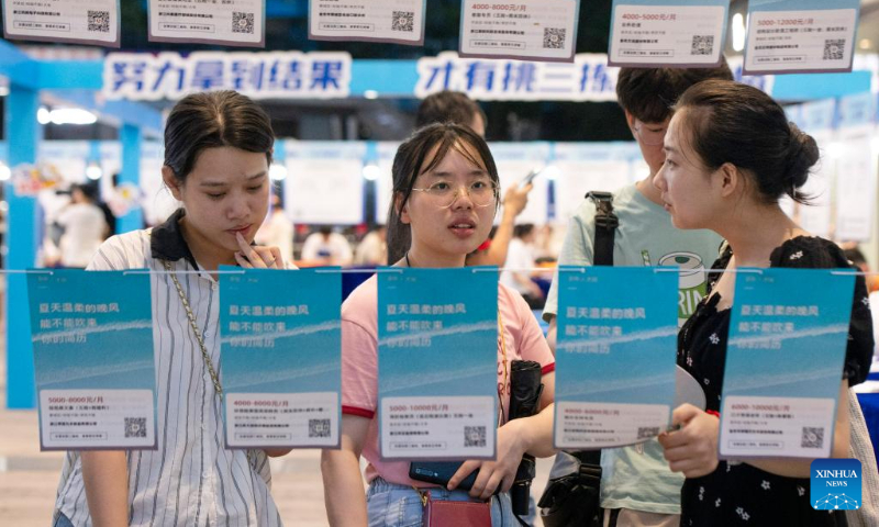 Job seekers read recruitment information at a job fair for college graduates in Jinhua City, east China's Zhejiang Province, July 21, 2023. (Photo by Shi Kuanbing/Xinhua)