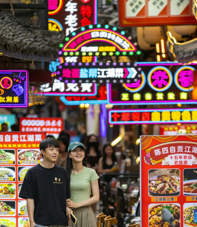 Visitors walk past the signboards of a gourmet street in Chengdu of southwest China's Sichuan Province, on June 11, 2023. The 31st FISU Summer World University Games is scheduled to take place in Chengdu from July 28 to August 8, 2023. (Xinhua/Shen Bohan)