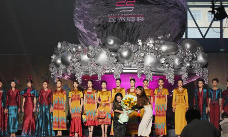 Designer Tao Tao takes a bow during the curtain call at a fashion show on the sidelines of the 6th China Xinjiang International Dance Festival, in Urumqi, northwest China's Xinjiang Uygur Autonomous Region, July 22, 2023. (Xinhua/Zhang Xiaocheng)