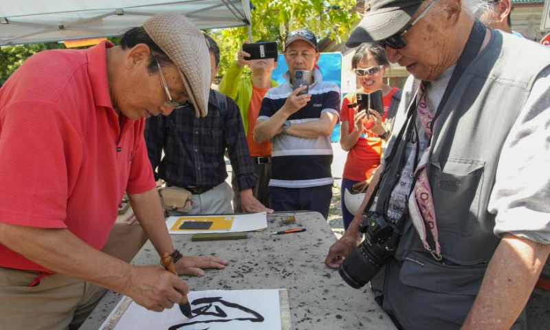 People watch Chinese calligraphy demonstration during the 21st Chinatown Festival in Vancouver, British Columbia, Canada, on July 15, 2023. The two-day community family event kicked off on Saturday here. (Photo by Liang Sen/Xinhua)