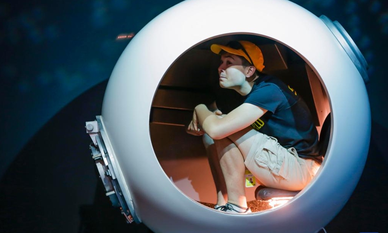 A visitor sits inside the pilot sphere of the Deepsea Challenger designed by James Cameron during James Cameron-Challenging the Deep exhibition at Science World in Vancouver, British Columbia, Canada, on July 10, 2023. James Cameron-Challenging the Deep is an immersive exhibition that showcases the filmmaker's achievements and innovations in deep-sea exploration and filmmaking.(Photo: Xinhua)