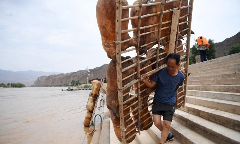 A ferry man carries a sheepskin raft as he prepares for rafting at the Yellow River Stone Forest Scenic Spot in Jingtai County of Baiyin City, northwest China's Gansu Province, July 11, 2023. Yellow River Stone Forest Scenic Spot is famous for the view of the Yellow River, stone stalagmites, stone pillars, dessert as well as oases.(Photo: Xinhua)