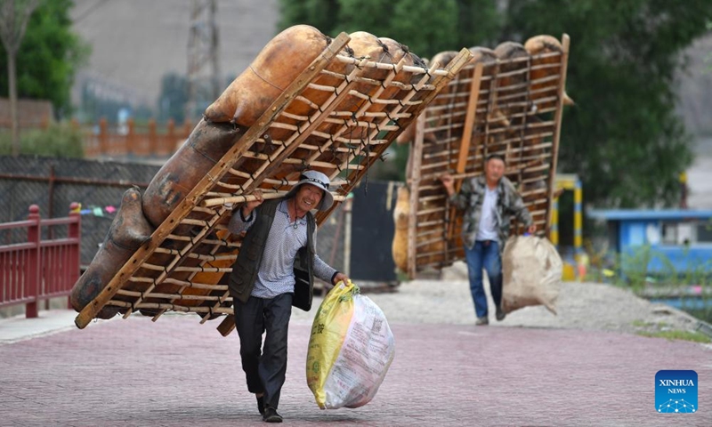 Ferry men carry sheepskin rafts for rafting at the Yellow River Stone Forest Scenic Spot in Jingtai County of Baiyin City, northwest China's Gansu Province, July 11, 2023. Yellow River Stone Forest Scenic Spot is famous for the view of the Yellow River, stone stalagmites, stone pillars, dessert as well as oases.(Photo: Xinhua)